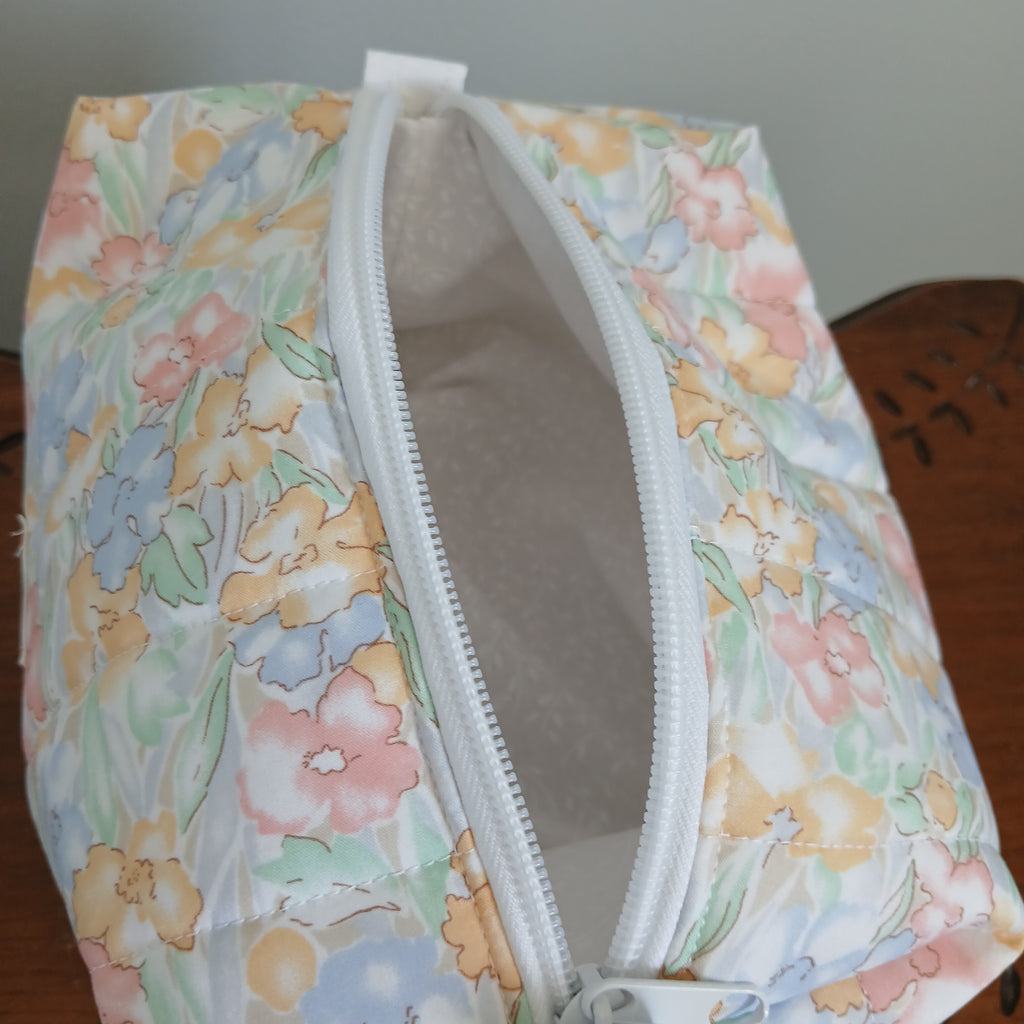 Floral-patterned pouch with a white zipper on a wooden surface