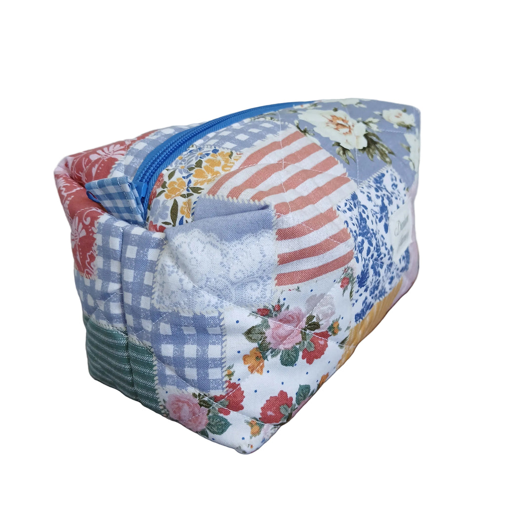 Fabric patchwork pouch with floral and checkered patterns on a wooden surface.
