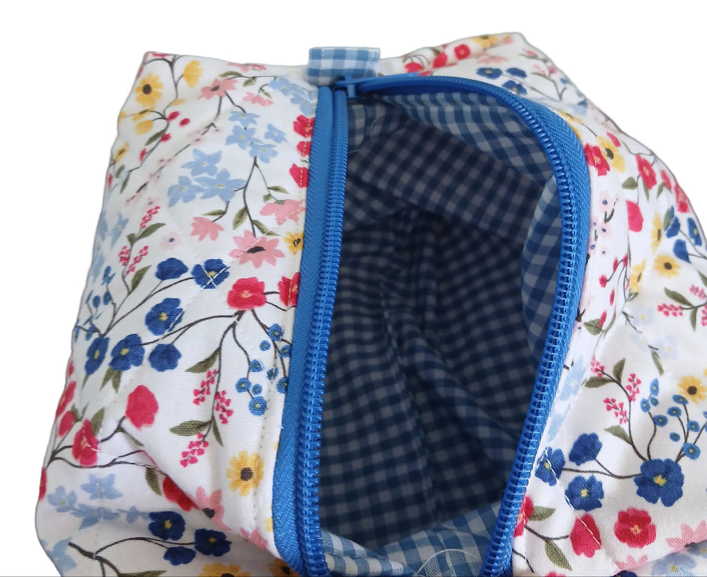 Floral-patterned fabric pouch with blue zipper on a plain background