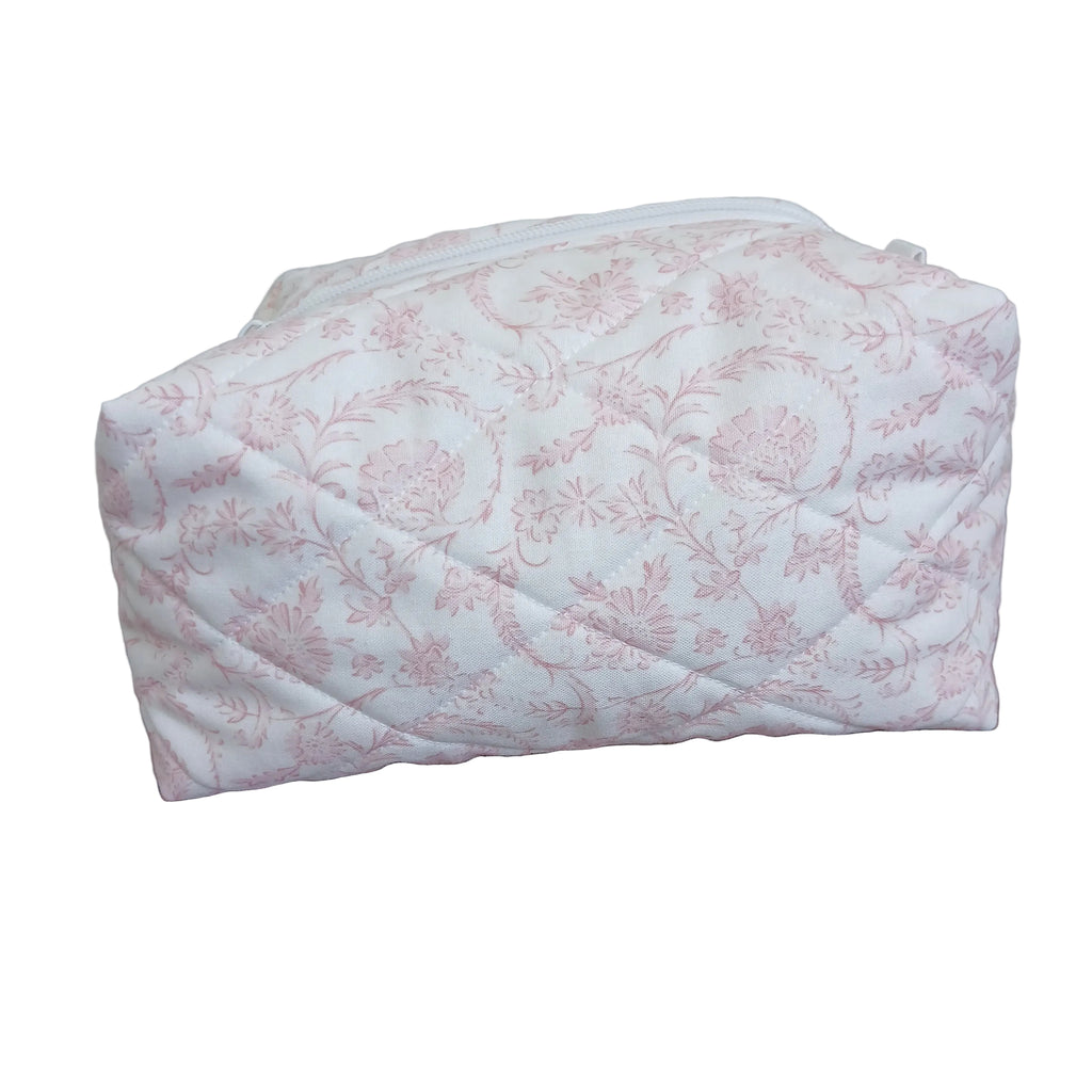 Floral-patterned quilt draped over a wooden chair against a neutral wall.