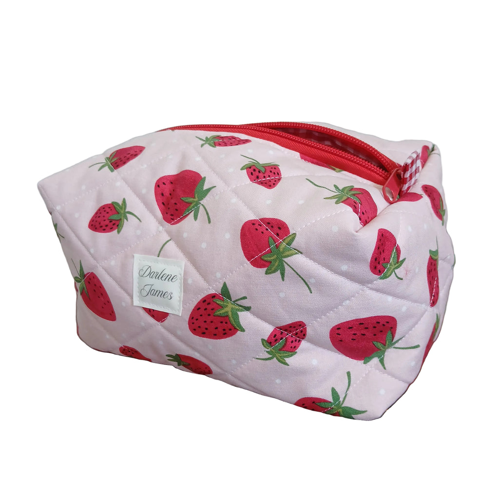 Pink pouch with strawberry pattern and a red zipper